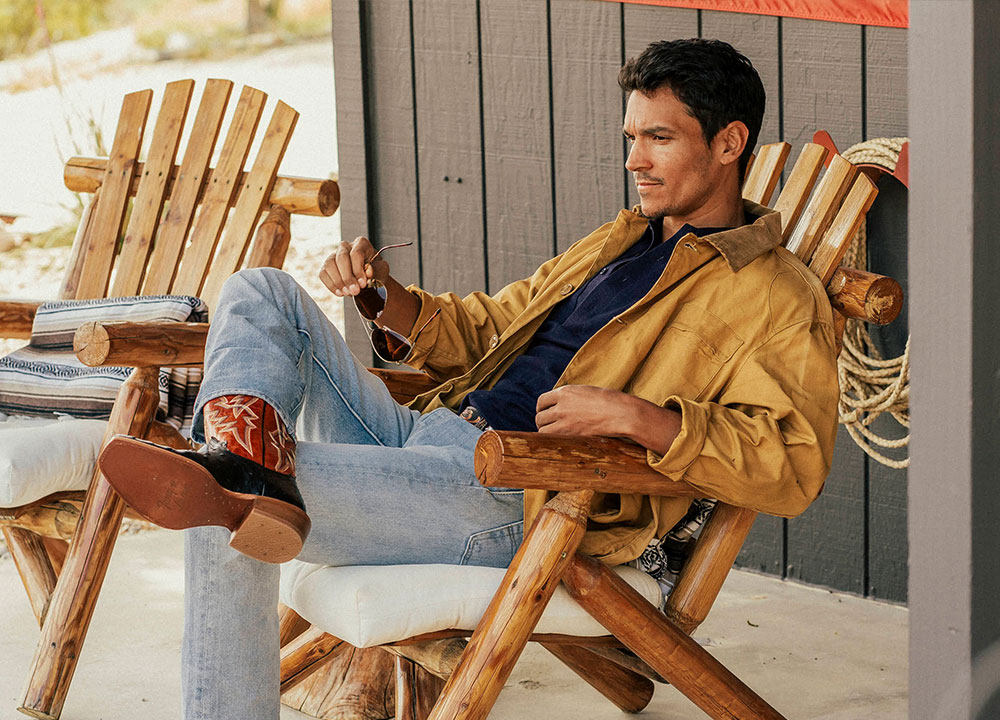A man sitting on his porch wearing the Rylen 13" Full Quill western boots in brown